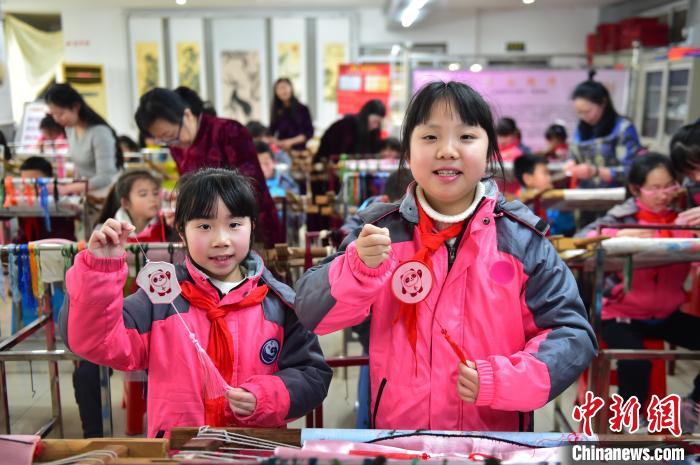 圖為小學生展示繡制好的2022年北京冬奧會吉祥物“冰墩墩”形象?！∮髟屏?攝