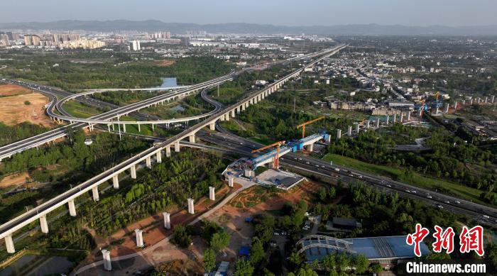 航拍正在建設(shè)的跨越成都繞城高速公路連續(xù)梁施工現(xiàn)場，旁邊依次為已運(yùn)營的成渝高速鐵路和機(jī)場高速公路?！⒅铱?攝