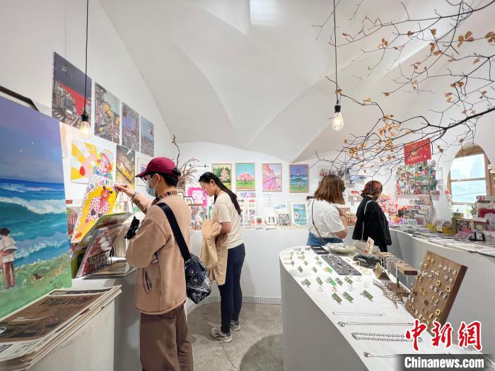 圖為藝術(shù)品商店內(nèi)，顧客挑選插畫作品?！＄婌?攝
