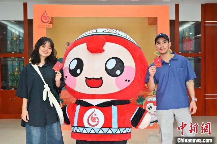 圖為泰國留學(xué)生手持獻血證與人偶合影?！∮峋?攝
