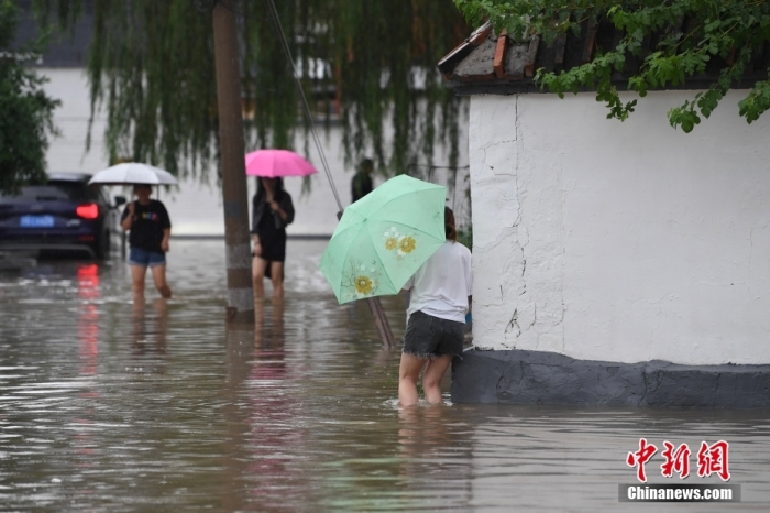 7月31日，市民行走在雨中的北京房山區(qū)瓦窯頭村。北京市氣象臺當日10時發(fā)布分區(qū)域暴雨紅色預警信號。北京市水文總站發(fā)布洪水紅色預警，預計當日12時至14時，房山區(qū)大石河流域將出現(xiàn)紅色預警標準洪水。<a target='_blank' href='/'><p  align=