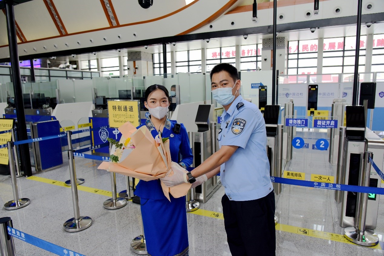 磨憨出入境邊防檢查站民警為中老鐵路第100萬(wàn)名出入境旅客，D888次國(guó)際旅客列車(chē)?yán)蠐爰藙?wù)員森達(dá)拉·妮緹婭（Sengdala Nitiya），送上鮮花。黃遠(yuǎn)飛 攝