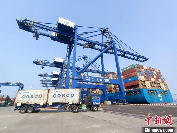 圖為海南洋浦國際集裝箱碼頭，卡車將集裝箱從后方堆場運(yùn)往碼頭裝卸區(qū)。　張?jiān)潞?攝