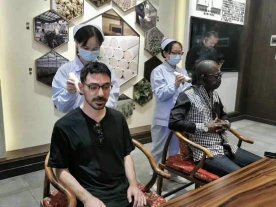 2023“一帶一路”媒體合作論壇聯(lián)合采訪團團員在九牛草展示館體驗艾灸。（本報記者 黃超攝）