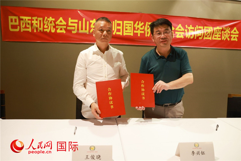 中國僑聯(lián)副主席、山東省僑聯(lián)主席李興鈺（右）與巴西和統(tǒng)會會長王俊曉簽署合作協(xié)議書。人民網記者 陳海琪攝