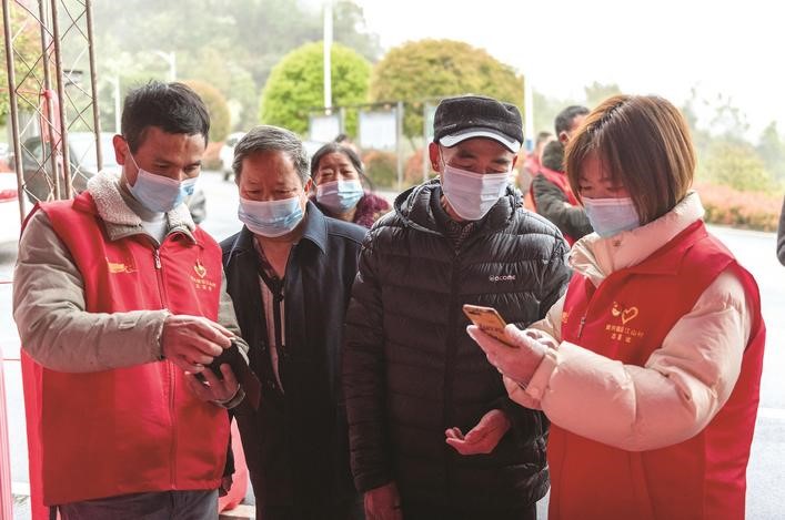 長(zhǎng)沙縣黨員志愿者正在幫助參與核酸檢測(cè)的群眾掃描“場(chǎng)所碼”。劉思源 攝