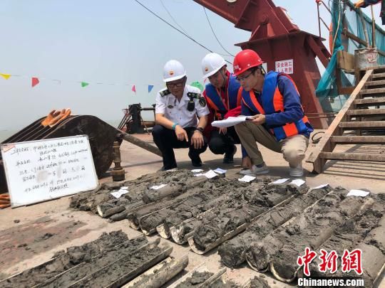 圖為勘察設(shè)計人員與海事局工作人員查看巖芯情況?！∥赫?攝