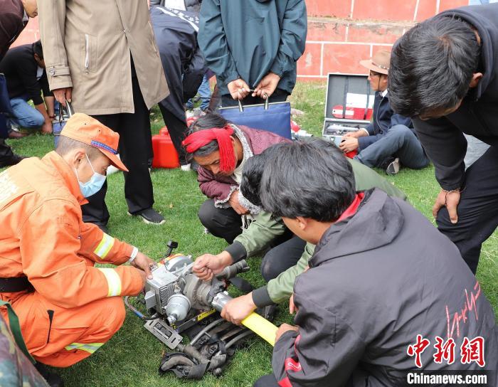 圖為森林消防員為護(hù)林員講解滅火裝備的使用方法?！〔际猩窒乐ш?duì) 供圖