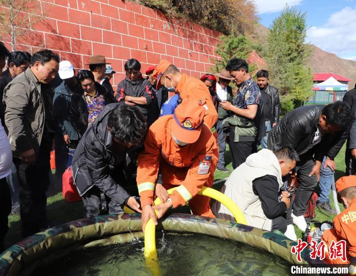 圖為森林消防員為護(hù)林員講解滅火裝備的使用方法?！〔际猩窒乐ш?duì) 供圖