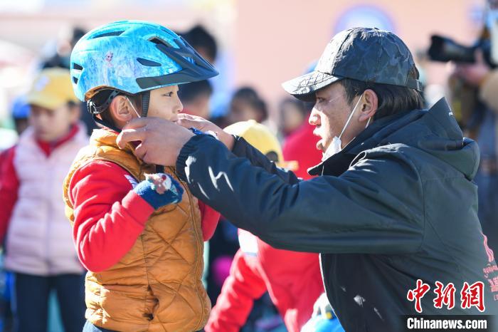 圖為拉薩市實(shí)驗(yàn)幼兒園孩子在教練的幫助下穿戴頭盔?！『闻罾?攝