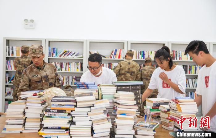 圖為志愿者們和邊防戰(zhàn)士整理圖書?！詵| 攝