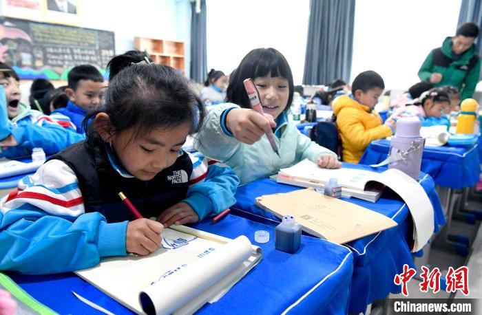 3月14日，西藏拉薩市第一小學一年級六班學生白瑪朗珍(圖左)在藏語文課上書寫藏文。　李林 攝