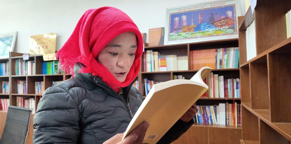 一名婦女正在認(rèn)真閱讀書籍。申扎縣融媒體中心供圖