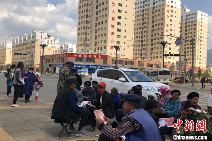 圖為會澤縣城易地扶貧搬遷安置點內(nèi)，老人們聚在廣場上聊天，身后是他們的新家?！】姵?攝