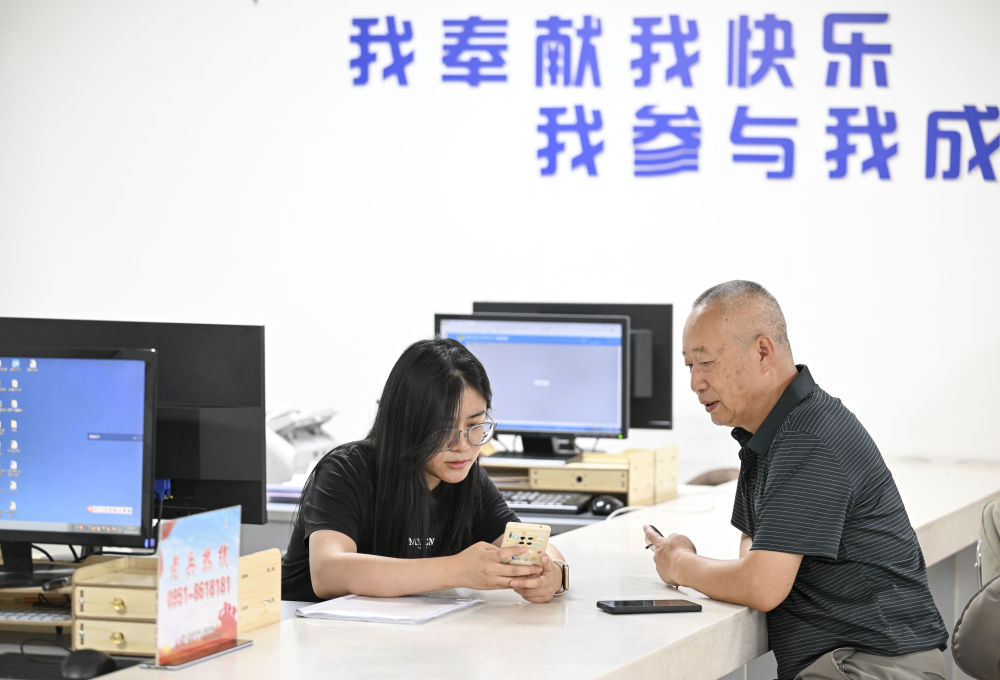 2024年6月20日，在寧夏銀川市金鳳區(qū)長城花園社區(qū)黨群服務(wù)中心，工作人員幫助居民辦理業(yè)務(wù)。圖片來源 新華社