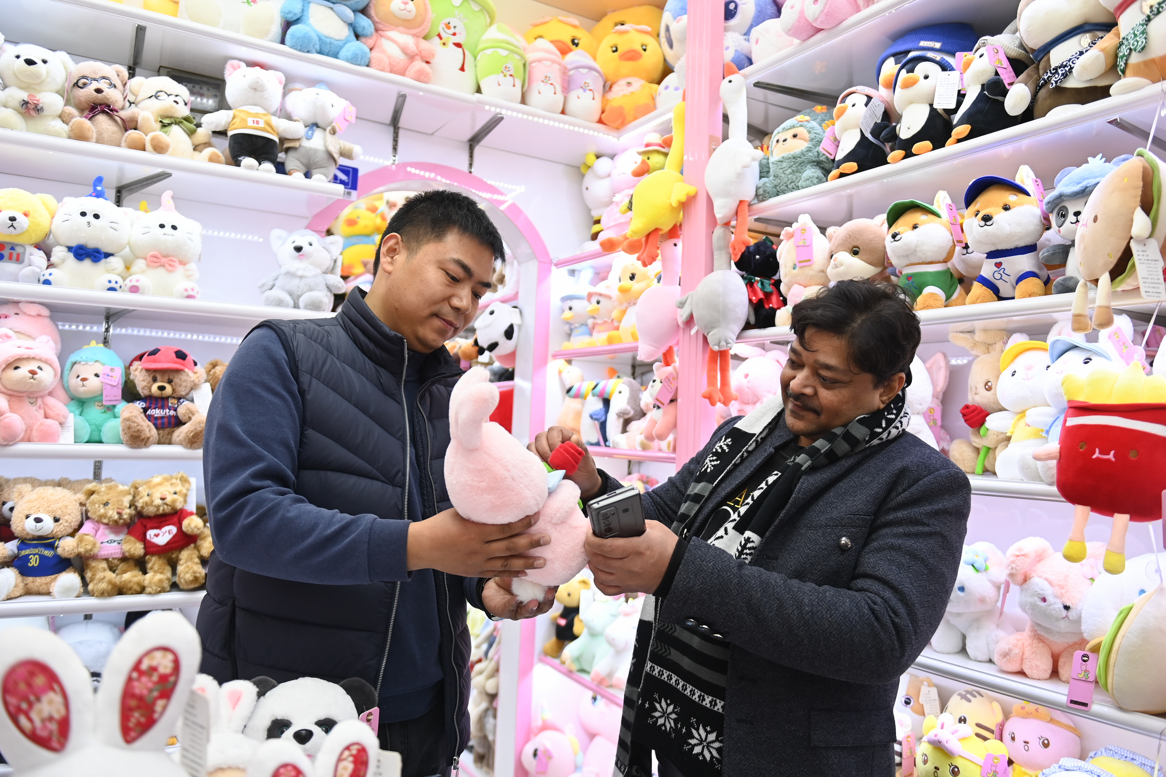 2023年2月2日，來自印度的客商（右）在義烏國際商貿(mào)城的一家玩具店鋪內(nèi)選購。
