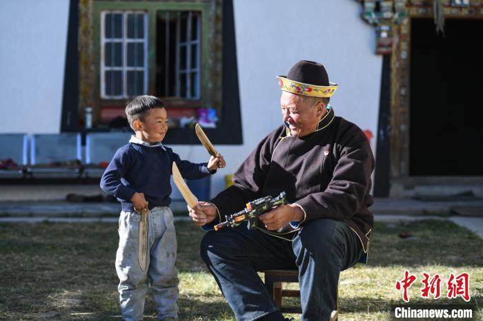 圖為米林縣扎西繞登鄉(xiāng)彩門村64歲的洛桑帶著孫子巴桑在院子的草地上玩耍。　何蓬磊 攝
