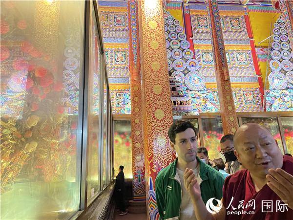 7月25日，省級(jí)非物質(zhì)文化遺產(chǎn)項(xiàng)目塔爾寺酥油花的代表性傳承人朋措堅(jiān)參（右）在塔爾寺酥油花館講解酥油花的制作過(guò)程。人民網(wǎng) 謝瑩攝
