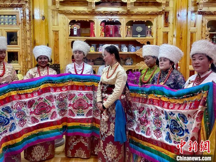 圖為女性展示村民自發(fā)繡制的“百米五彩哈達”?！±钣穹?攝