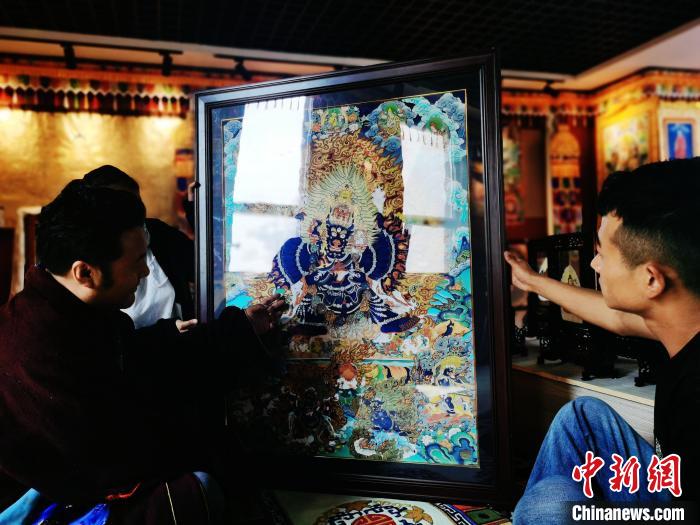 圖為久美尖措(左)與徒弟們展示唐卡作品?！?zhí)砀?攝