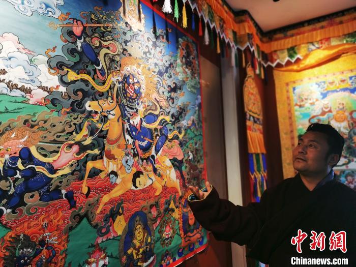 圖為久美尖措展示唐卡作品?！?zhí)砀?攝