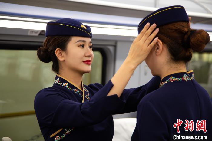 圖為青藏鐵路西格段“復(fù)興號”動車組乘務(wù)員互相整理新制服。　李磊 攝