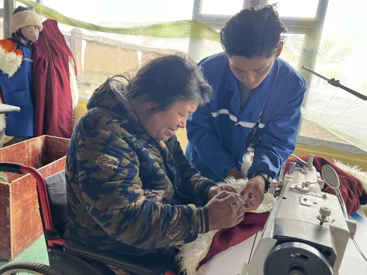 扎西奪爾登幫助殘疾員工裁剪。阿壩州文明辦供圖