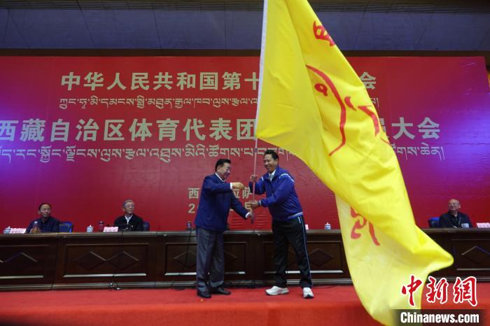 西藏自治區(qū)副主席甲熱·洛桑丹增授代表團團旗，西藏自治區(qū)體育局局長尼瑪次仁接旗?！∪轿木?攝