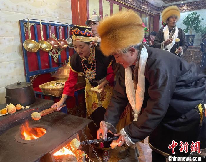 圖為人們在火上烤節(jié)日美食“結(jié)達”?！∪轿木?攝