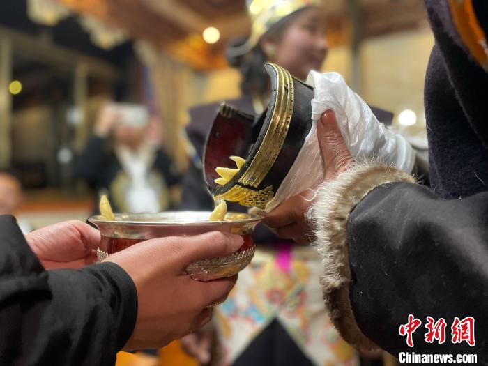 圖為主人在碗中斟滿青稞酒?！∪轿木?攝