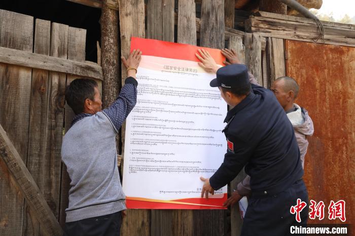 圖為亞?wèn)|邊檢站民警與駐地邊民群眾共同張貼國(guó)家安全知識(shí)教育海報(bào)。　亞?wèn)|邊檢站 供圖