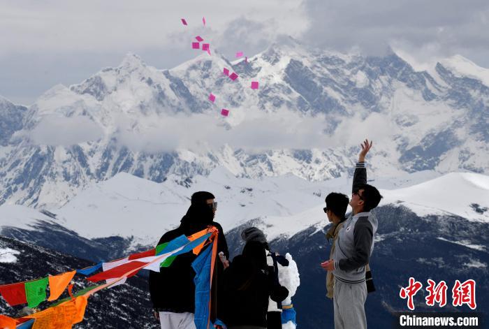 圖為5月14日，游客在西藏林芝色季拉山觀景臺拋灑“隆達(dá)”(風(fēng)馬旗，藏族民眾的一種祈福方式)。　李林 攝